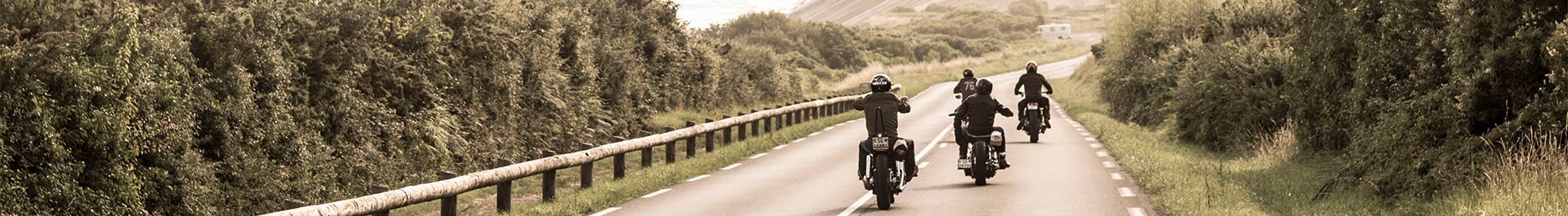 Header-Bild Unterseite Produkte Moto And More Motorradfahrer in lederner Bekleidung auf einer Straße